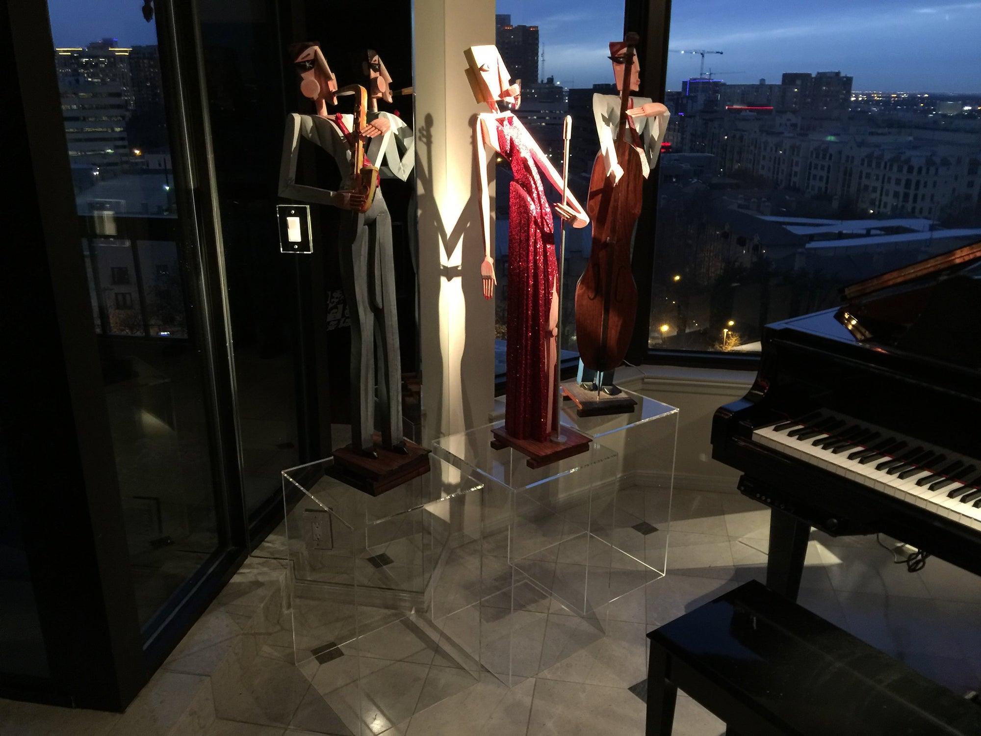 Three clear acrylic pedestals with an abstract jazz band sculpture on them.